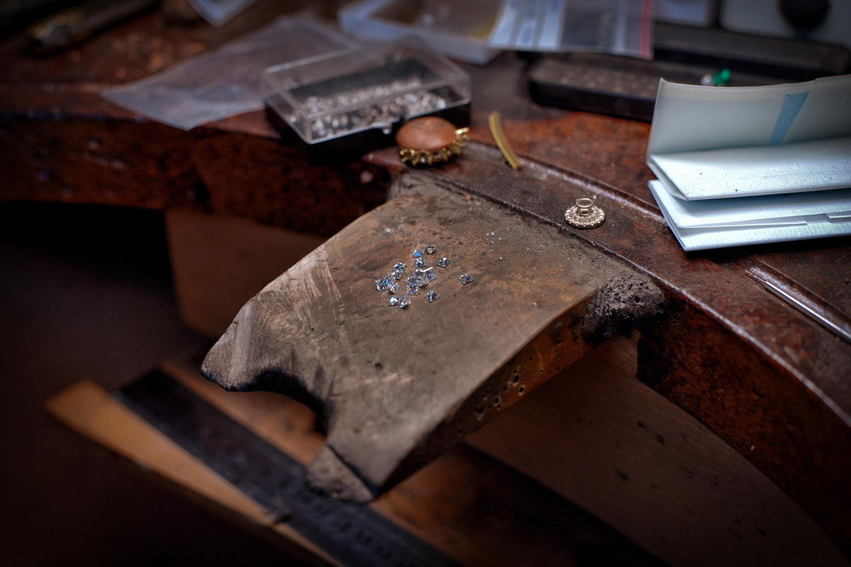 Des diamants sont posés sur l'établis de l'atelier, prêt à être sertis dans un bijou unique rien que pour vous. 